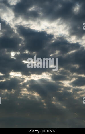 Bedrohlich, ominösen dunklen grauen Himmel mit ein paar Sonnenstrahlen hell weißen peeping durch eine Lücke in den Wolken. Stockfoto