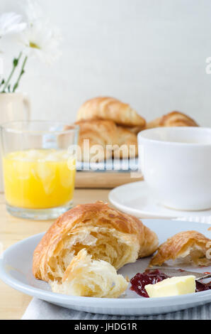 Tischdekoration kontinentales Frühstück mit Croissants, Orangensaft, Kaffee und Blumen gelegt. Eine Portion von teilweise gegessen Croissant mit Butter und Marmelade Stockfoto