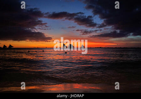 Schöner roten Sonnenuntergang Himmel spiegelt sich in ruhigen Meer und Sand.  Der Himmel über den Sonnenuntergang ist ein Fett blau eingerahmt von stürmischen Wolken. Boracay-Philippinen Stockfoto