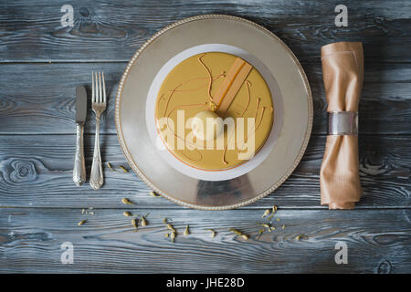 Frisch gebackenen gelben Pudding Kuchen mit Mandel-Dacquoise, Himbeer-Confit, knusprige Schicht mit karamellisierten Haselnüssen und Himbeere Pulver, mousse auf Bitterschokolade serviert auf Holztisch Stockfoto