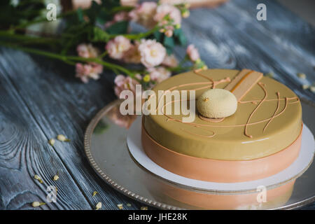 Frisch gebackenen gelben Pudding Kuchen mit Mandel-Dacquoise, Himbeer-Confit, knusprige Schicht mit karamellisierten Haselnüssen und Himbeere Pulver, mousse auf Bitterschokolade serviert auf Holztisch Stockfoto