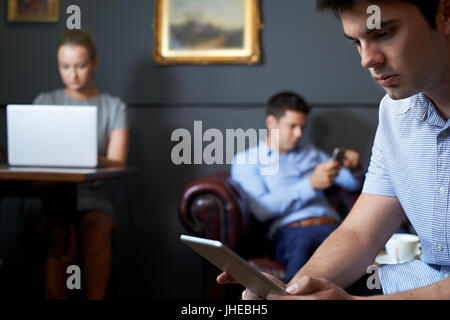 Geschäftsleute, die mit digitalen Geräten im Cafe Stockfoto