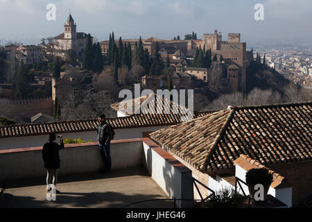 Zwei Touristen fotografieren in den Generalife-Palast (Palacio del Generalife) mit dem Palast Komplex der Alhambra in Granada, Andalusien, Spanien im Hintergrund zu sehen. Stockfoto