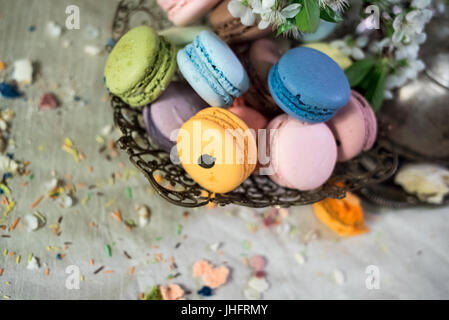 Multicolor Makronen auf einem Tisch mit östlichen Vase und Kirsche Niederlassung in Blüte Stockfoto