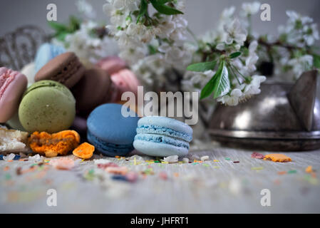 Multicolor Makronen auf einem Tisch mit östlichen Vase und Kirsche Niederlassung in Blüte Stockfoto