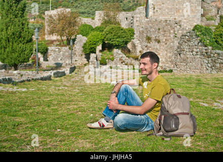 junger Mann sitzt auf dem Rasen in alten bar Fort, Montenegro Stockfoto