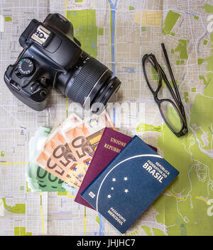 Planen Sie eine Reise - brasilianische und italienische Pässe auf Stadt Karte mit Euro Rechnungen Geld, Kamera und Gläser Stockfoto