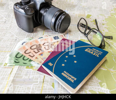 Planen Sie eine Reise - brasilianische und italienische Pässe auf Stadt Karte mit Euro Rechnungen Geld, Kamera und Gläser Stockfoto