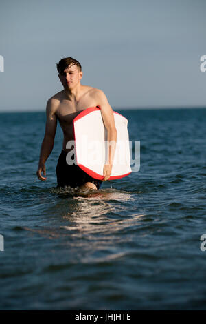 Teenager mit einem Bodyboard im Meer Stockfoto