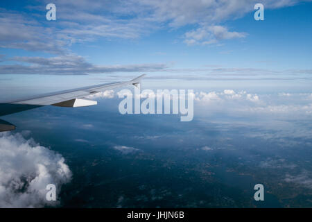 über den Wolken fliegen hoch auf Flugzeug-Fenster-Ansicht Stockfoto