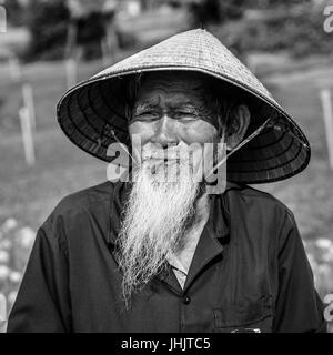 Bärtiger Alter Mann von Vietnam in einem konischen Hut - schwarz / weiß Stockfoto