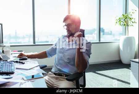 Junge Unternehmer auf der Suche auf dem Computer-Bildschirm mit Konzentration an seinem Schreibtisch. Geschäftsmann in nachdenklicher Stimmung sitzt an seinem Schreibtisch. Stockfoto