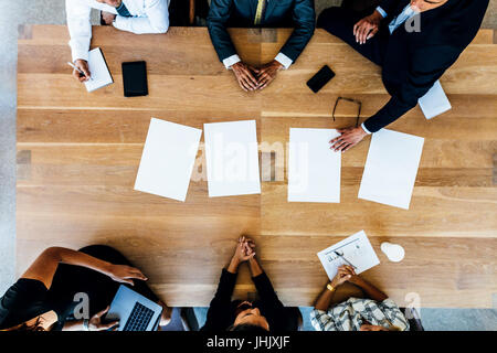 Draufsicht der Geschäftsleute sitzen um einen Tisch mit leere Blätter. Multi-ethnischen Business-Profis treffen. Stockfoto