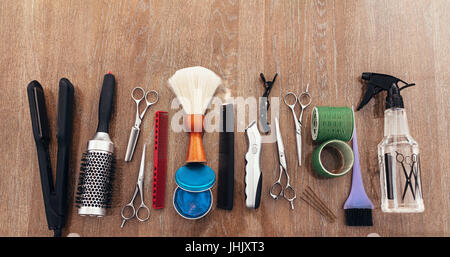 Professioneller Friseur-Tools auf der Holzoberfläche. Draufsicht der Friseur Zubehör in Linie angeordnet. Stockfoto