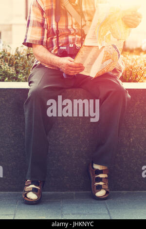 Rentner in Socken und Sandalen in Park Vintage Ziel auf Karte suchen Stockfoto