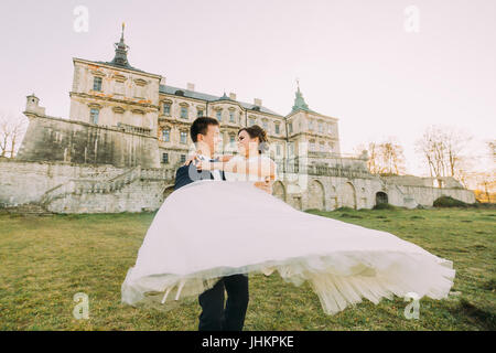 Just married Outdoor Portrait von der fröhlich auf den Hintergrund des antiken Palastes. Der Bräutigam dreht sich die Braut. Stockfoto