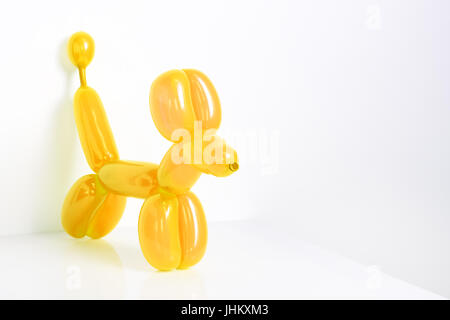 Einfache gelbe gedrehte Ballon Tiere Hund auf weiß. Spielzeug von Ballons, Freiraum für Text. Ballonkunst. Stockfoto