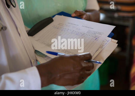 Ein Arzt überprüft eine Patienten-Noten auf der Station an einem regionalen Krankenhaus, Uganda. Stockfoto