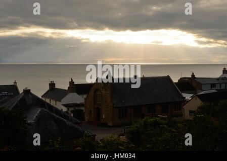 Die Sonne bricht durch die Wolken über den Dornoch Firth gesehen über die Dächer von Fischereidorf in Easter Ross, Schottland Stockfoto