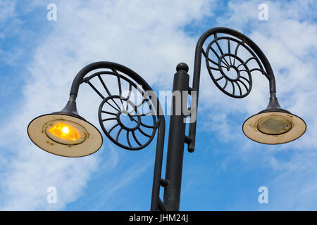 Reich verzierte Ammoniten Design Lampen spiegeln die Städte Lage an der Jurassic Coast, eine beleuchtete und eine nicht beleuchtet, auf Promenade bei Lyme Regis, Dorset Juli Stockfoto