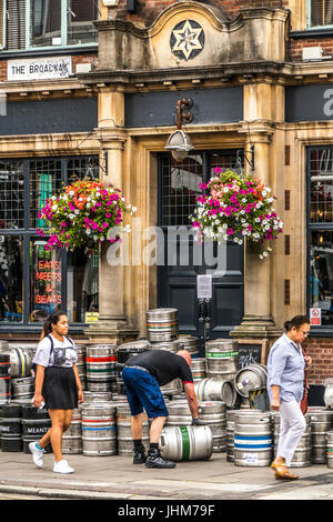 Eine Brauerei Anlieferung Treiber, Bierfässer außerhalb einer Kneipe in Ealing Broadway, London W5, England. UK. Stockfoto