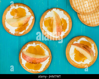 Weicher Ricotta-Käse mit Apfel und Honig auf einem Keks oder Cracker auf blauem Grund Stockfoto