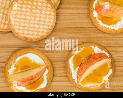 Weicher Ricotta-Käse mit Apfel und Honig auf einem Keks oder Cracker auf ein Schneidbrett aus Holz Stockfoto