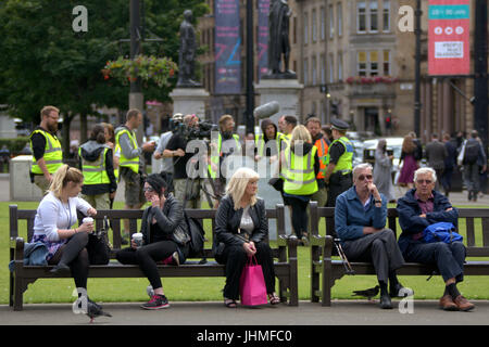 Glasgow, Schottland. 14. Juli. Dreharbeiten zu nonchalant ignoriert wurde heute von den Einheimischen, die jetzt immer verwendet, um Medien und Film Crews in der Stadt als Menschen ihre Mittagspause mit der neuesten Serie von BBC Scotland Spoof vorbei Komödie "Scot Polizeieinheit" wurde in der Stadt George Square erschossen, Credit: Gerard Fähre/Alamy Live News Stockfoto