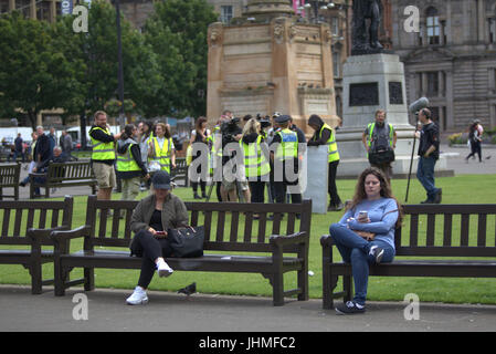 Glasgow, Schottland. 14. Juli. Dreharbeiten zu nonchalant ignoriert wurde heute von den Einheimischen, die jetzt immer verwendet, um Medien und Film Crews in der Stadt als Menschen ihre Mittagspause mit der neuesten Serie von BBC Scotland Spoof vorbei Komödie "Scot Polizeieinheit" wurde in der Stadt George Square erschossen, Credit: Gerard Fähre/Alamy Live News Stockfoto