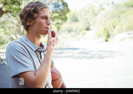 Mann mit Basketball Pfeifen in Basketballplatz aufhalten Stockfoto