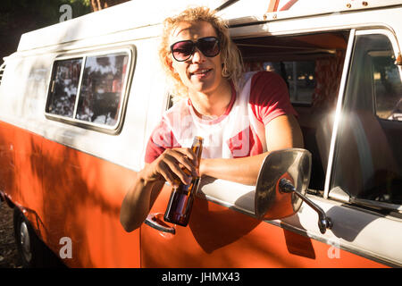 Porträt des Mannes mit Bier an Camper van Fenster gelehnt Stockfoto