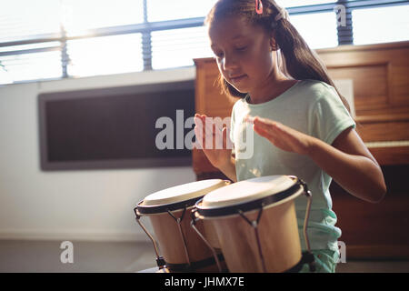 Mädchen spielt Bongo-Trommeln im Unterricht an der Musikschule Stockfoto