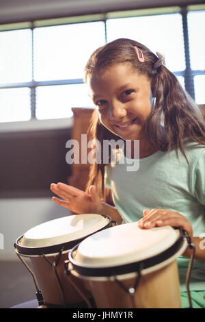 Porträt der lächelnde Mädchen spielt Bongo-Trommeln im Unterricht an der Musikschule Stockfoto