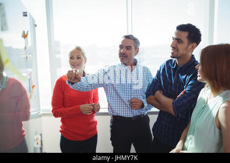 Unternehmer diskutieren über Whiteboard im Büro Stockfoto