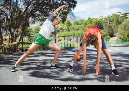 Freunde üben stretching Übung zur Straße gegen Baum Stockfoto