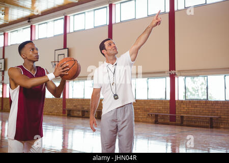 Trainer Ausbildung männlichen Teenager in Basketballplatz aufhalten Stockfoto