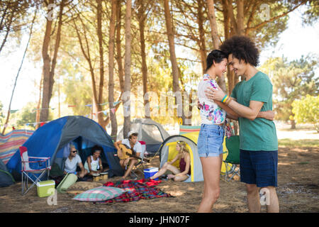 Seitenansicht des paar stehen von Angesicht zu Angesicht mit Freunden im Hintergrund auf Campingplatz Stockfoto