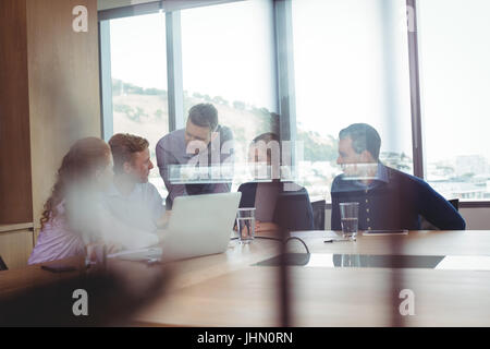 Business-Leute diskutieren im Sitzungsraum gesehen durch das Glas im Büro Stockfoto