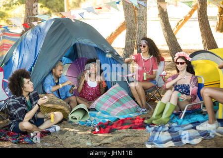 Glückliche junge Freunde genießen von Zelten auf Feld auf Campingplatz Stockfoto