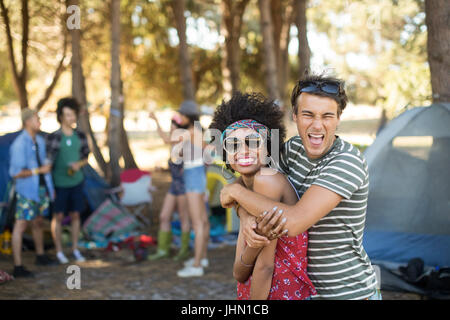 Porträt von fröhlichen jungen Freunde umarmen auf Campingplatz Stockfoto