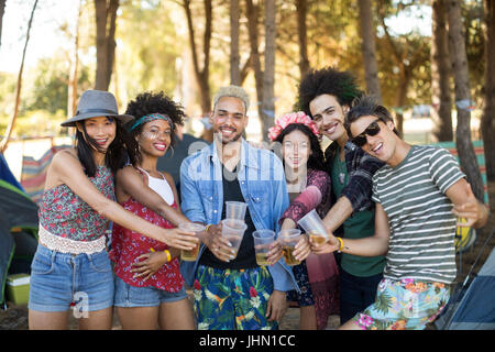 Porträt von lächelnden Freunde halten Biergläser auf Campingplatz Stockfoto