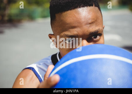 Porträt der männlichen Teenager halten Basketball an sonnigen Tag hautnah Stockfoto