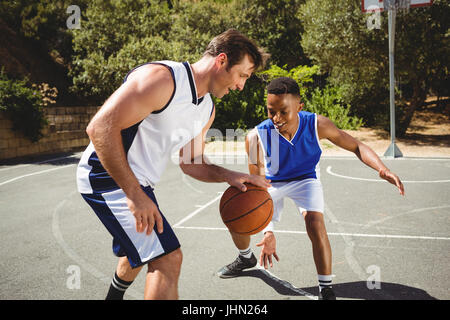 Glückliche Freunde spielen Basketball vor Gericht Stockfoto