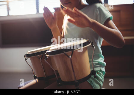 Mittelteil des Mädchens spielt Bongo-Trommeln im Unterricht an der Musikschule Stockfoto