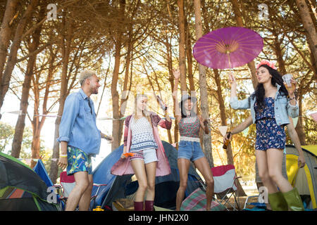 Niedrigen Winkel Ansicht der glückliche junge Freunde tanzen gegen Bäume am Campingplatz Stockfoto