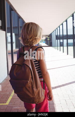 Rückansicht des Schuljunge mit Rucksack stehend im Flur in der Schule an sonnigen Tag Stockfoto