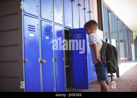 Seitenansicht der junge Stand von offenen Schrank im Flur in der Schule Stockfoto