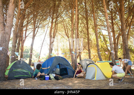 Freunde, die bunten Zelte am Campingplatz am sonnigen Tag einrichten Stockfoto