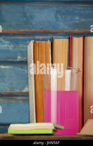 Stapel von Büchern, chemische Becher und Haftnotizen Hintergrund blau aus Holz Stockfoto