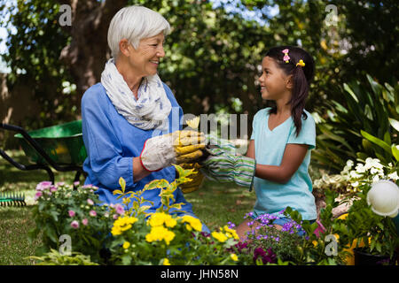 Lächelnden Großmutter und Enkelin sahen einander haltend Blume im Garten Stockfoto